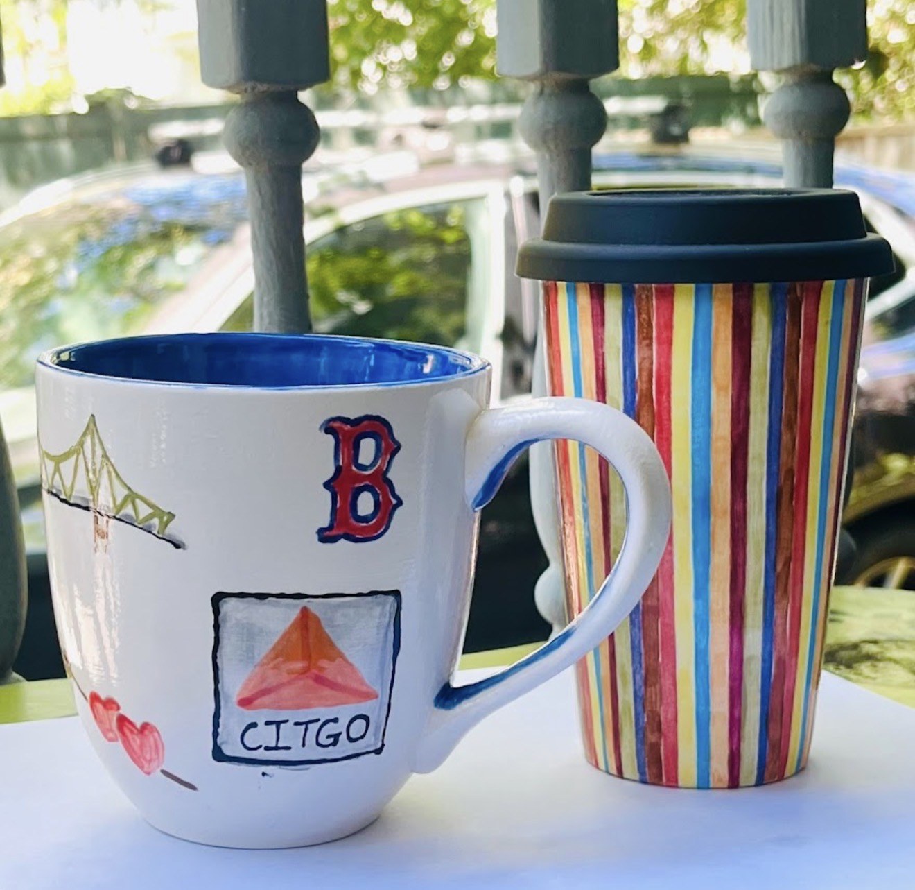 Boston-themed painted mug beside a colorful striped pottery piece