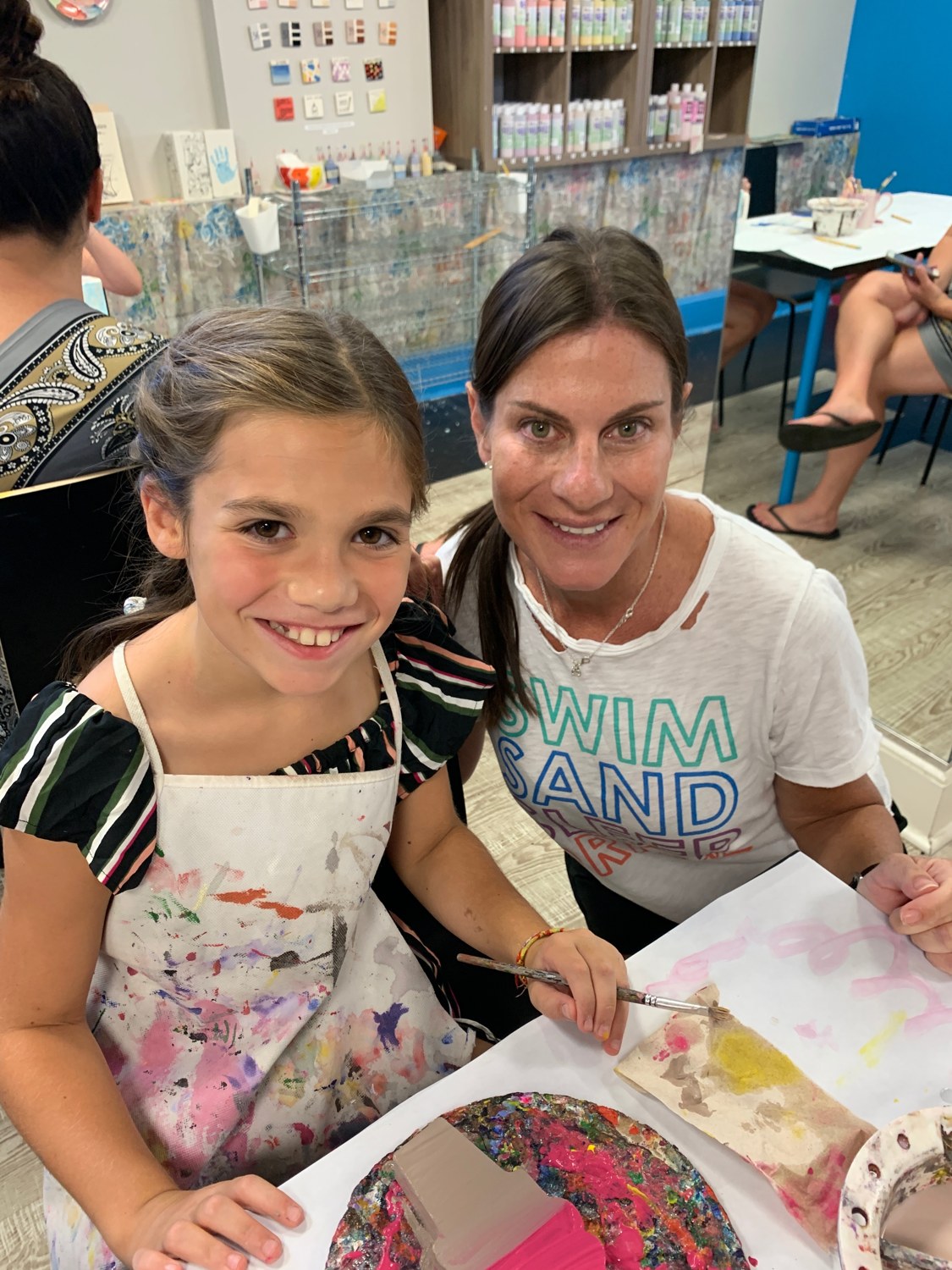 Samara and a young painter smiling while creating together at The Painting Place