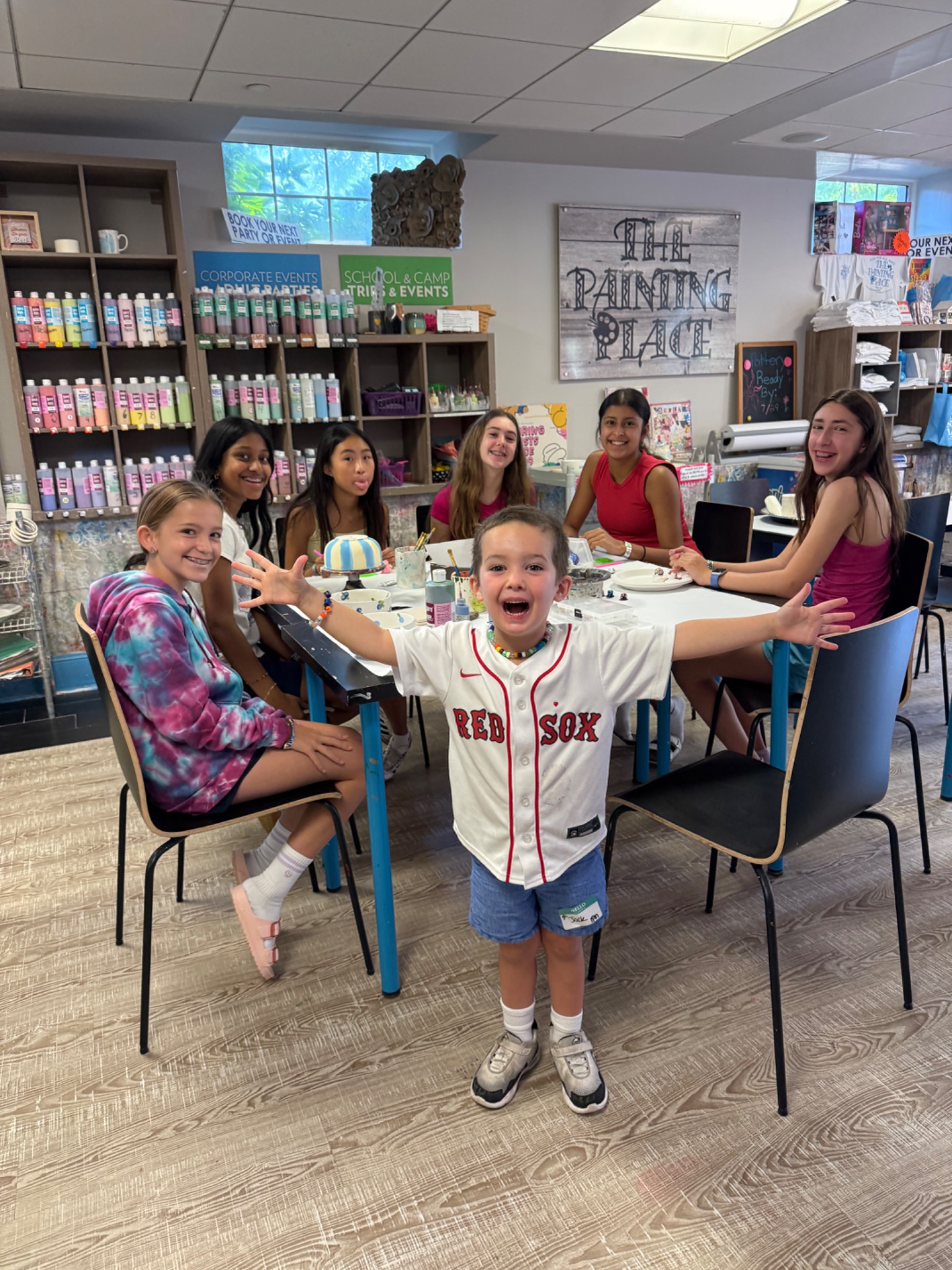 Kids painting and celebrating around a studio table at The Painting Place